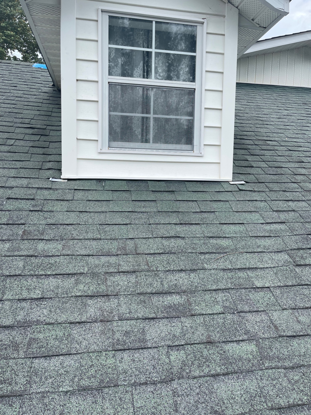 Wide view of a dormer window sitting above a completed asphalt shingle roof slope