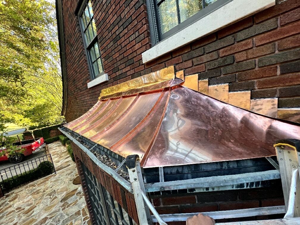 Custom copper bay window roof with stepped flashing on a brick home