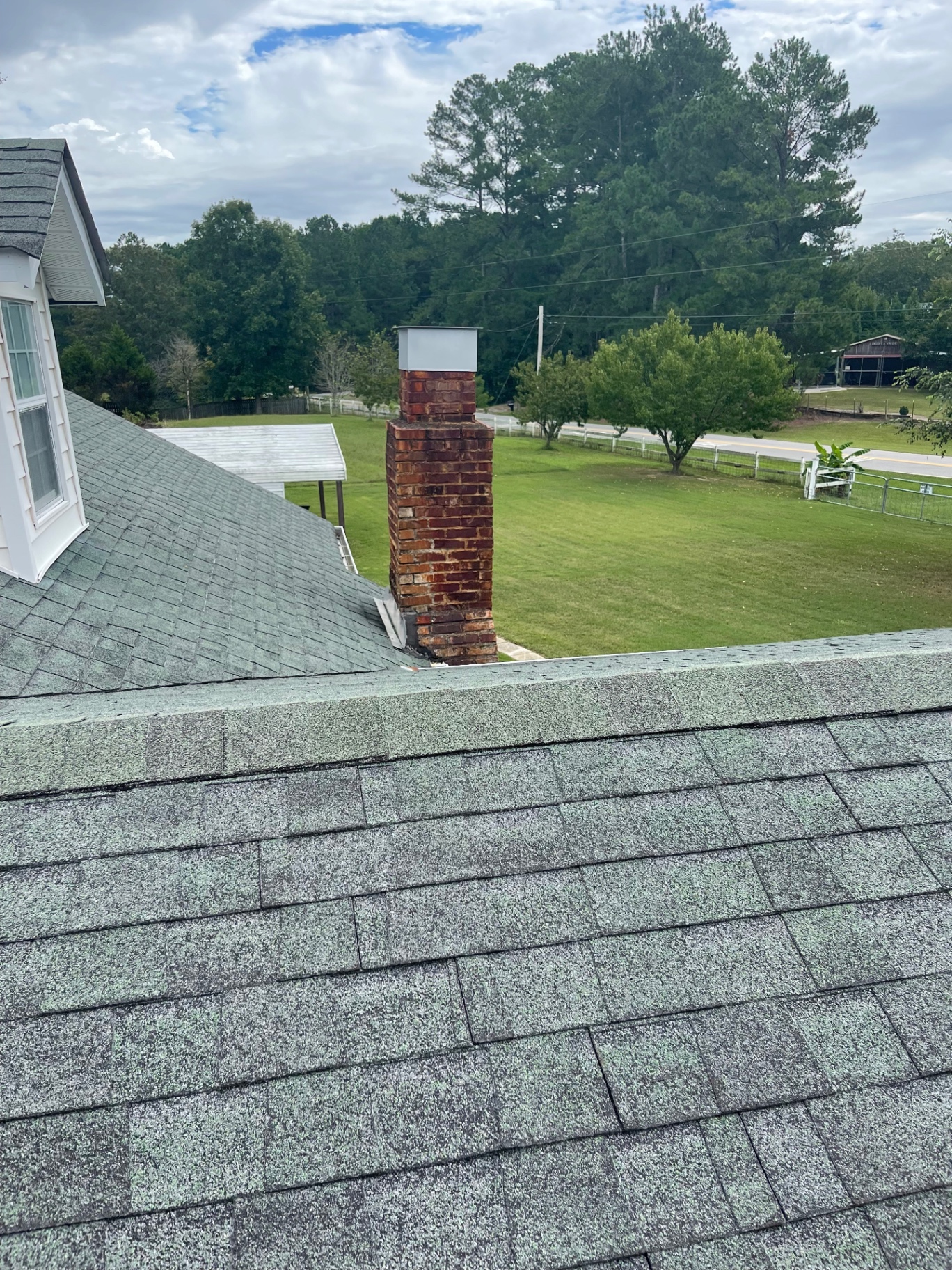 Roofline view with a brick chimney and surrounding shingle field during inspection