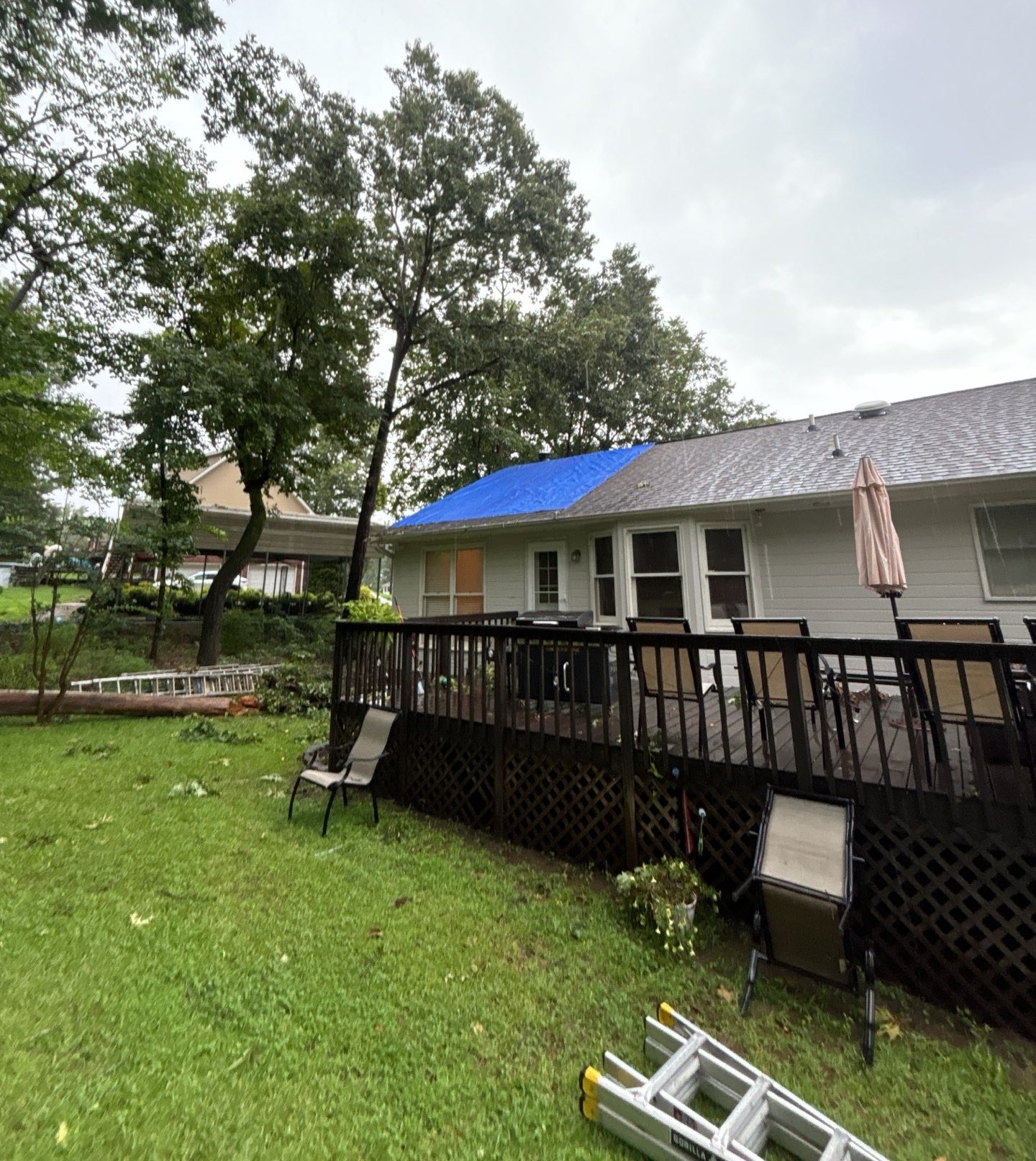 Storm-damaged roof covered with an emergency blue tarp