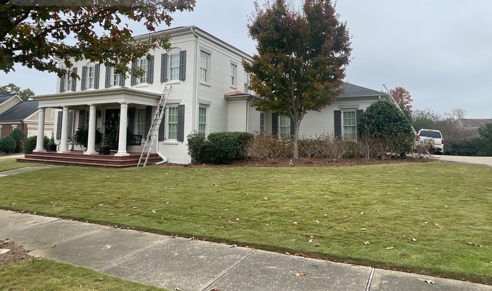 White brick estate with a completed roof replacement and manicured front lawn