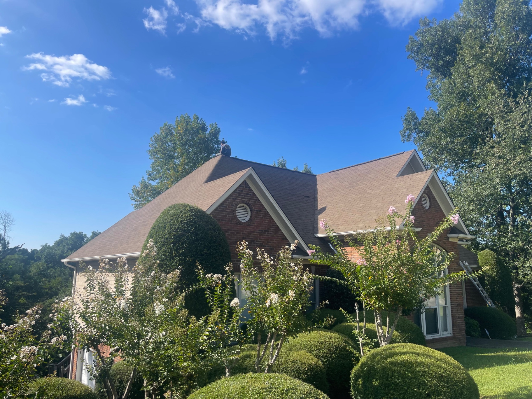 Front exterior of a brick home with Eagle crew performing roof and chimney work