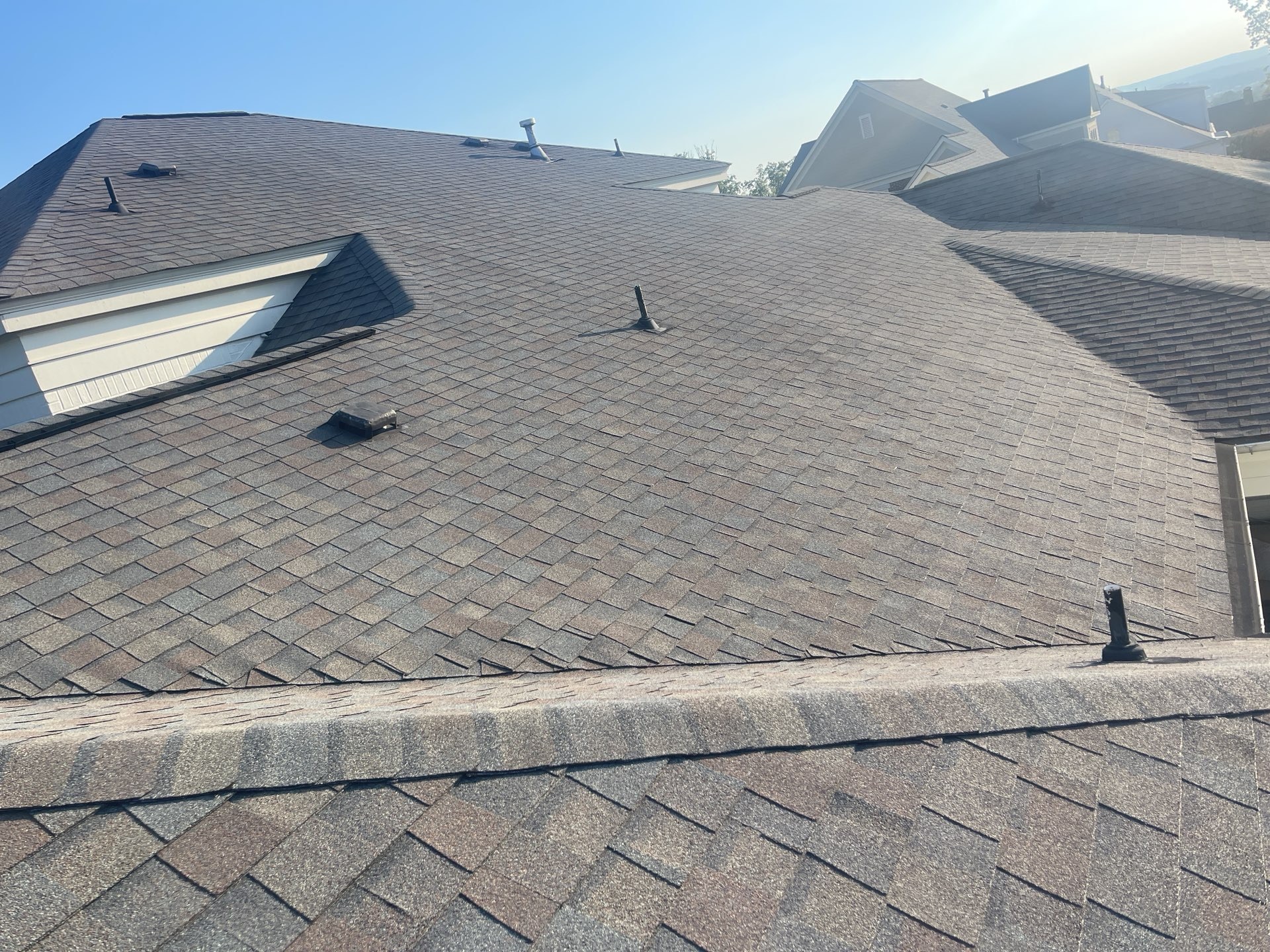 Wide overview of a completed brown architectural shingle roof on a large home