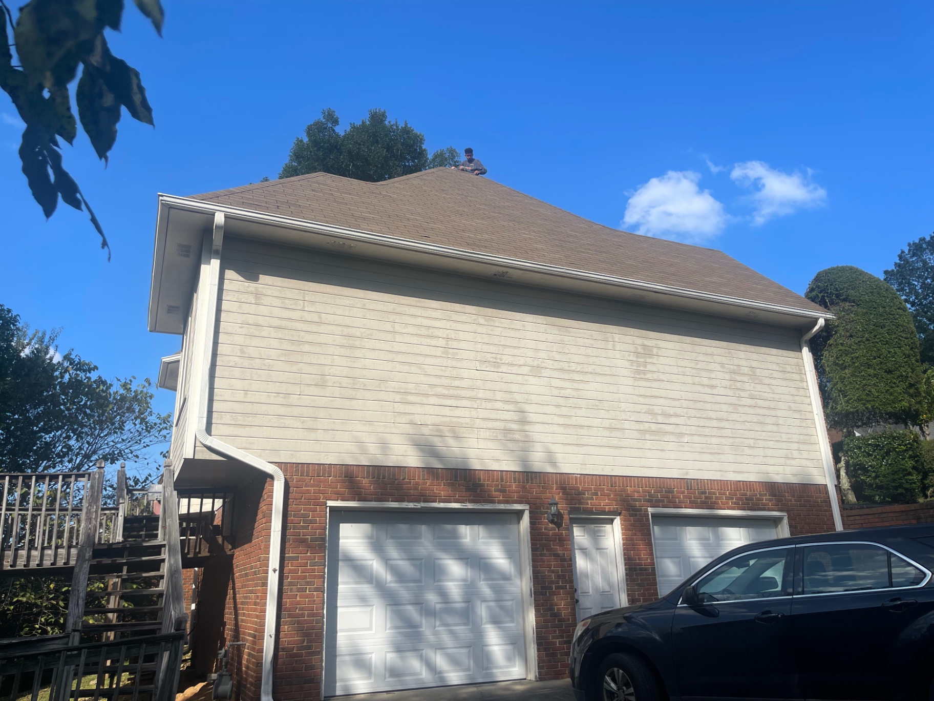 Side elevation of a home with Eagle crew working on the roof above the garage