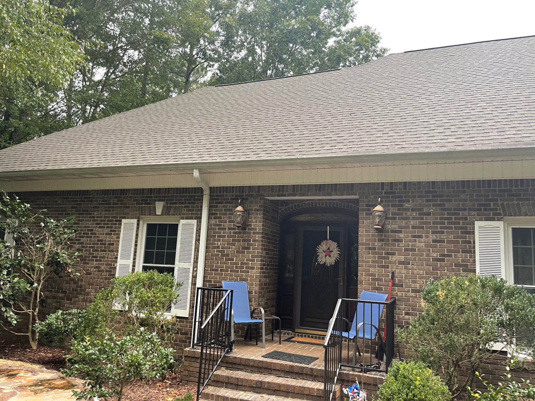 Front entry view of a brick home with a completed roof and clean shingle lines