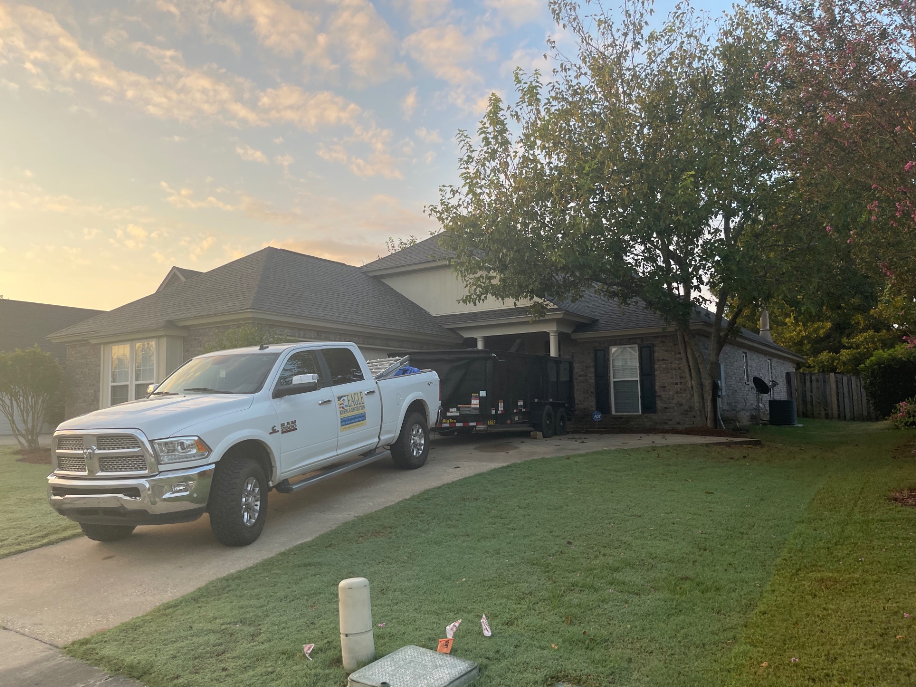 Suburban home at sunrise with Eagle Roofing truck and trailer parked ahead of project work