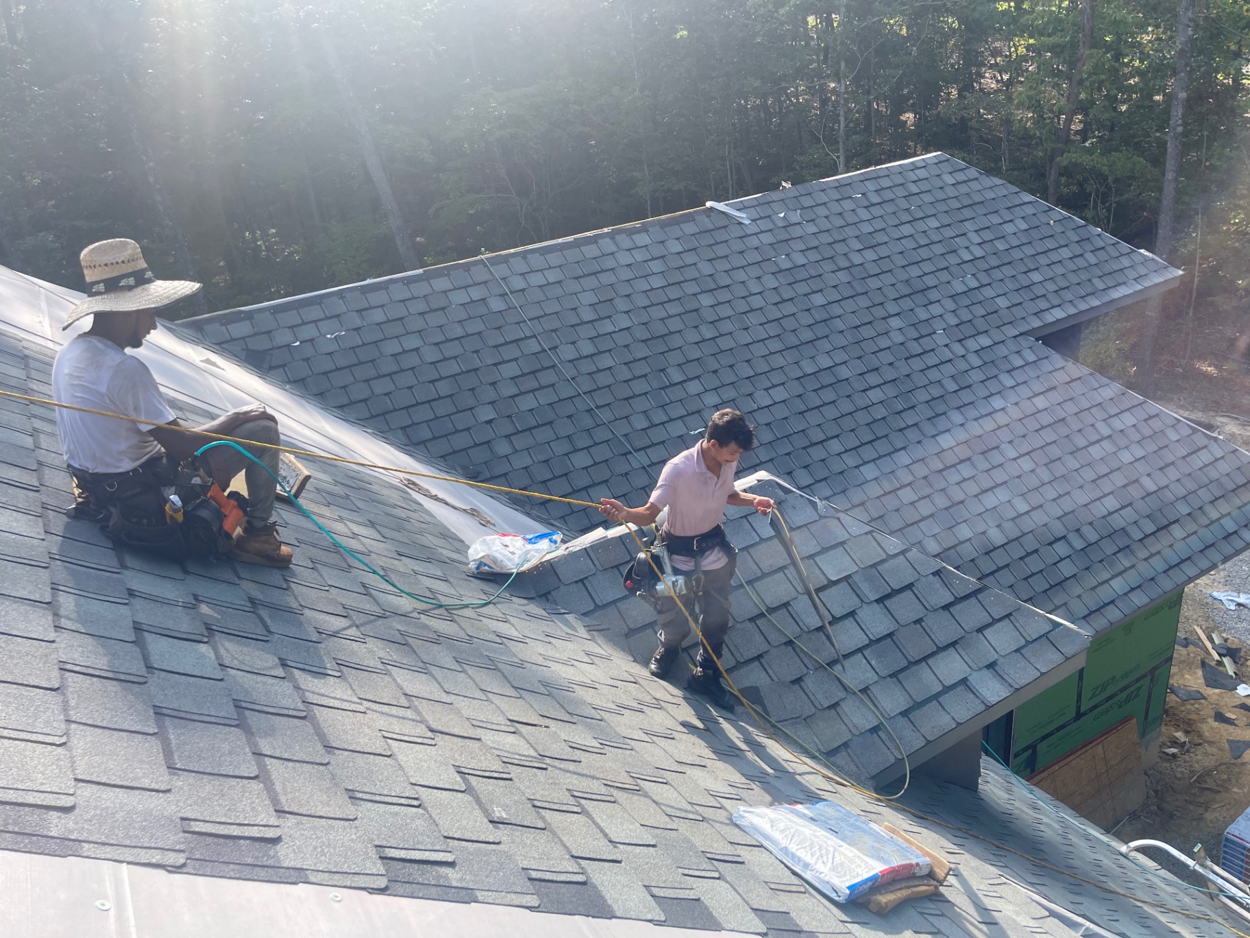 Eagle crew members installing shingles on a steep roof slope during a replacement