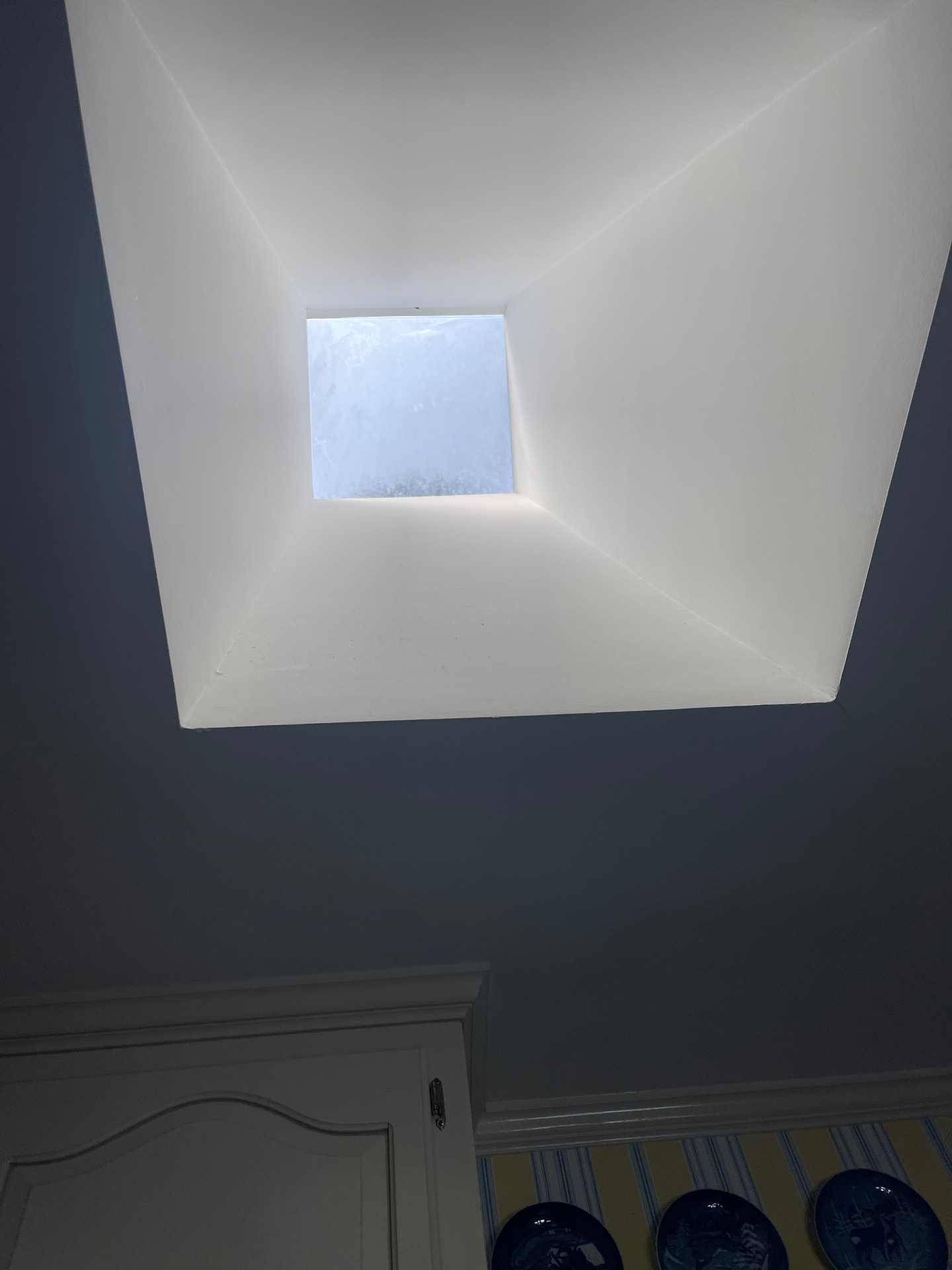 Interior view up through a finished skylight well bringing natural light into the home
