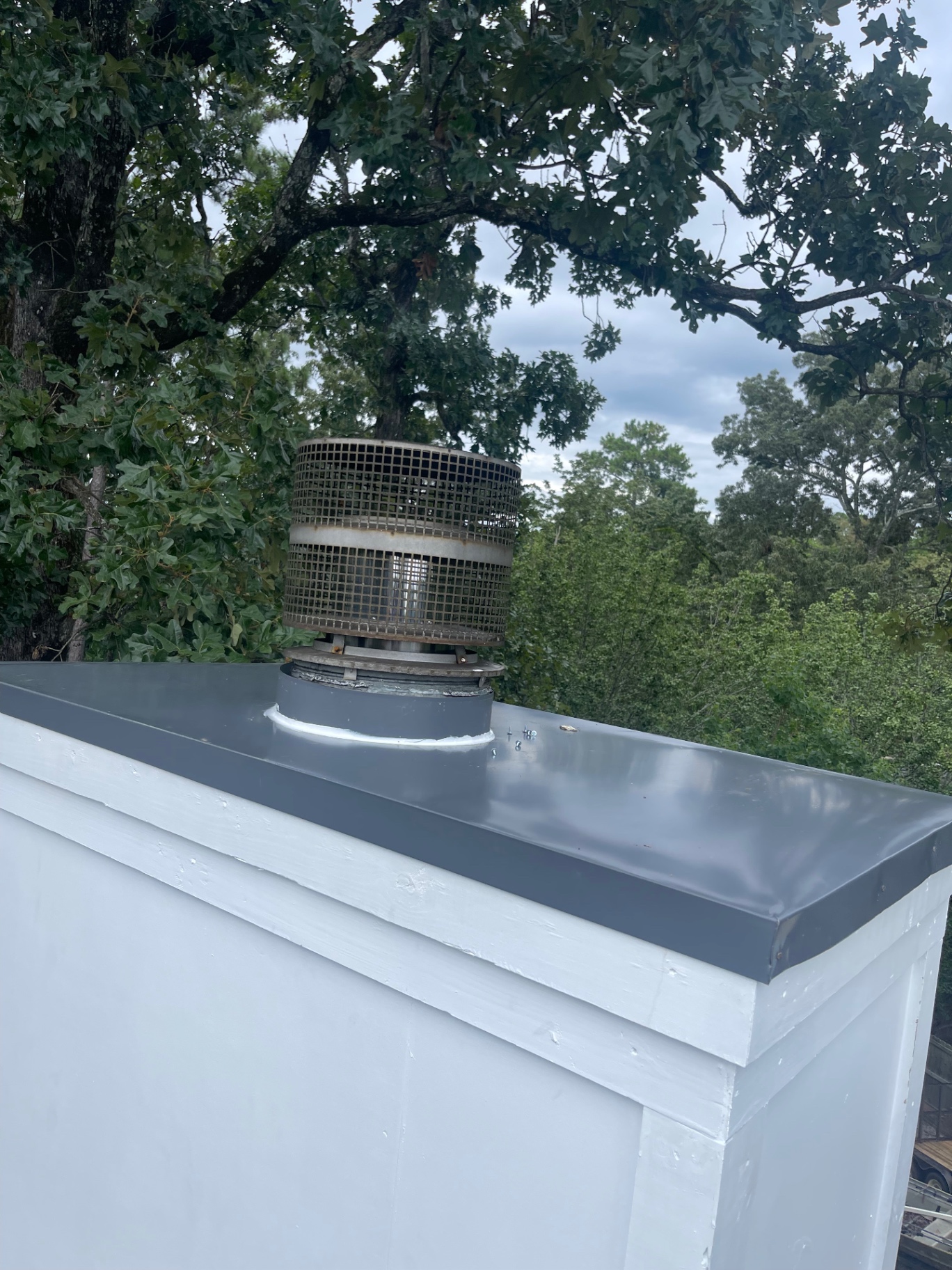 New chimney cap and spark arrestor installed on a freshly painted chase