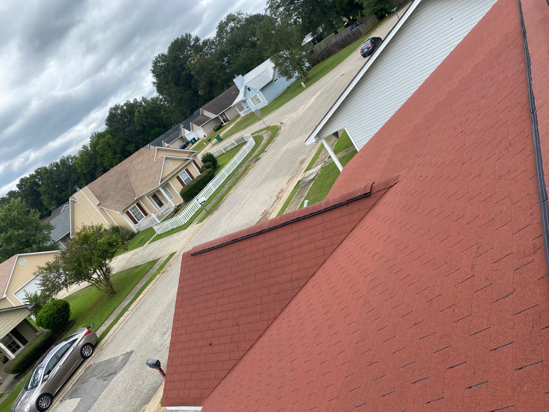 High-angle view across a completed red shingle roof in a residential neighborhood