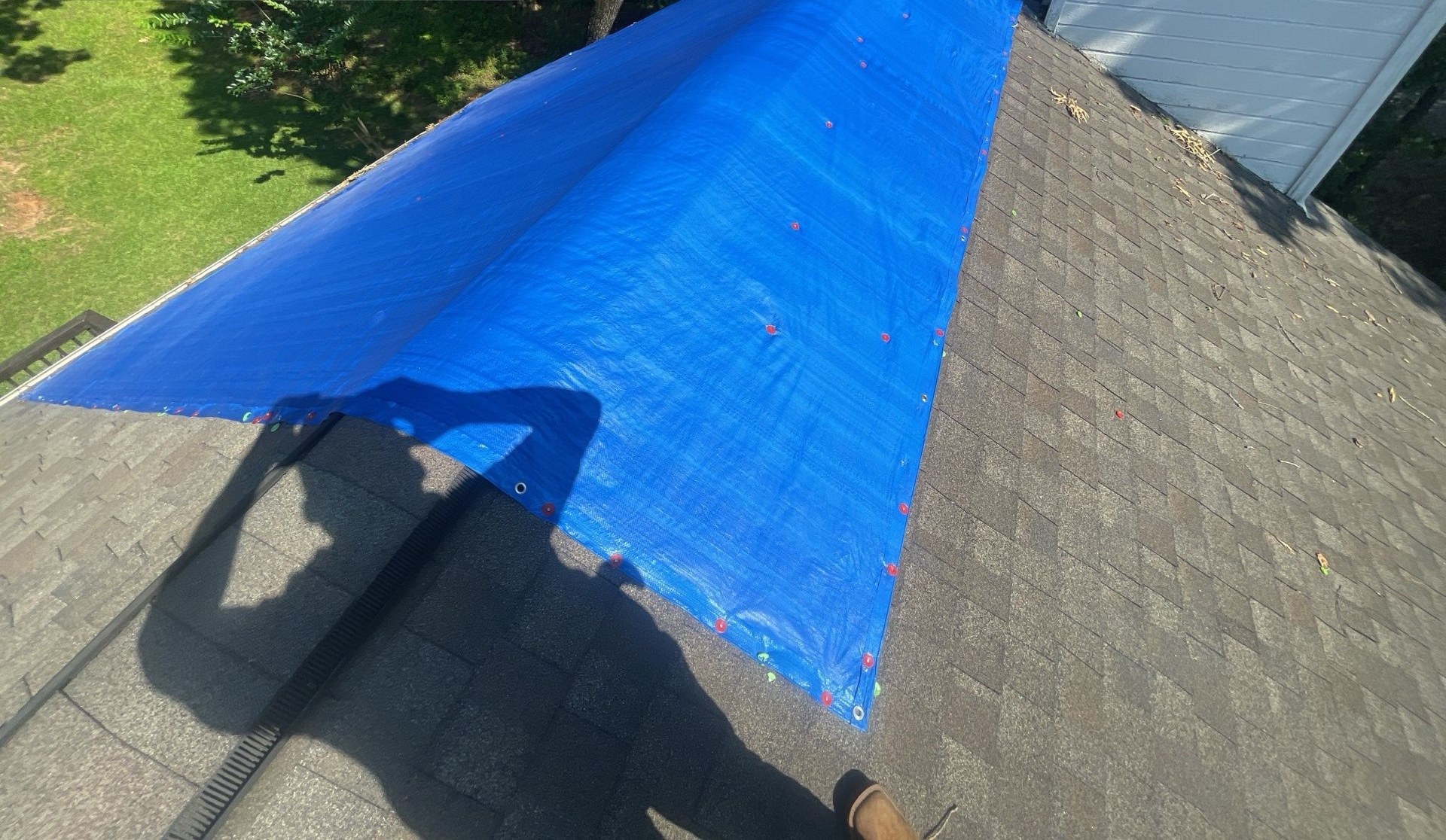 Hip roof protected with a blue tarp after storm damage