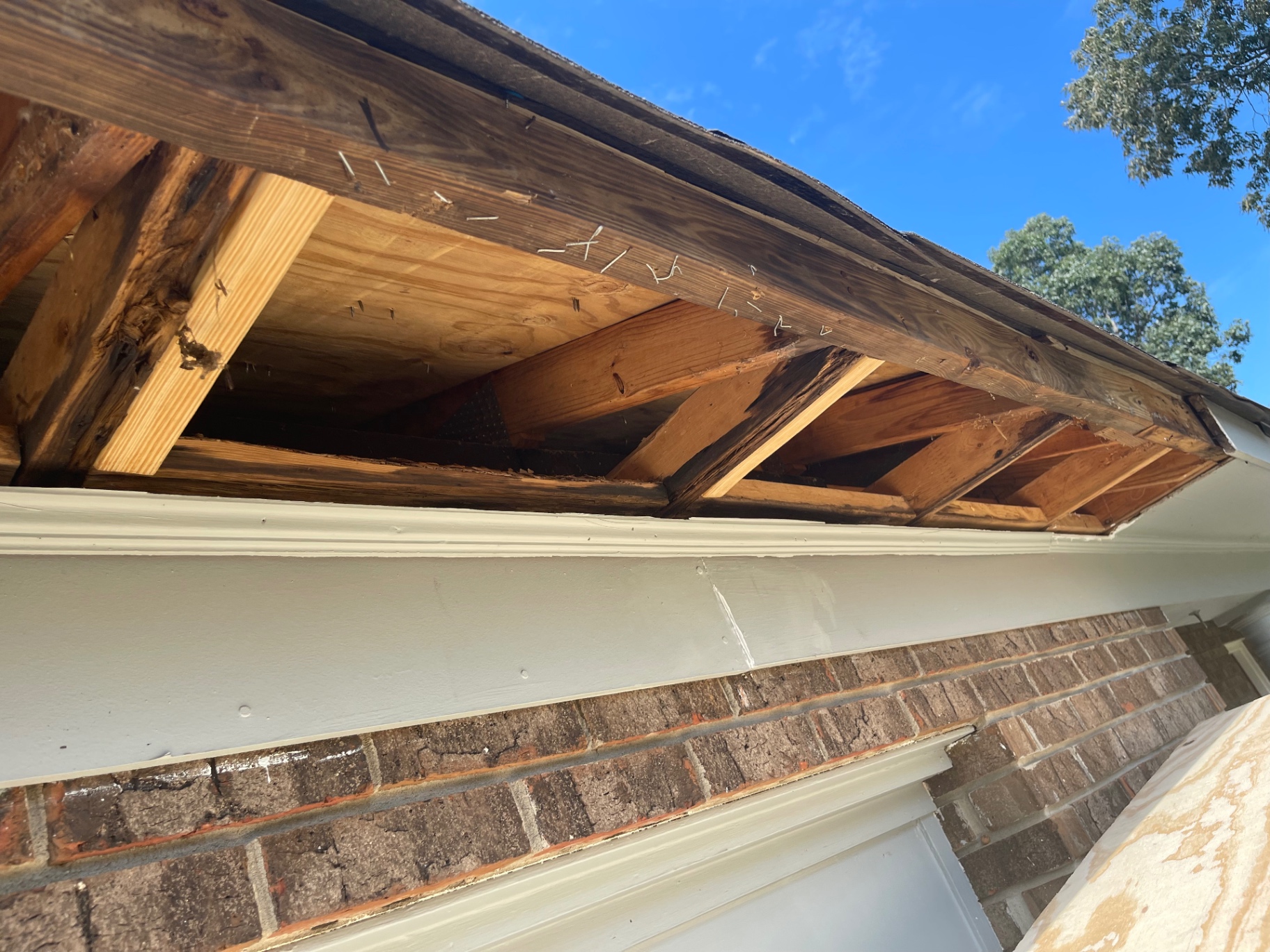 Open eave framing with visible wood rot and structural repair work in progress