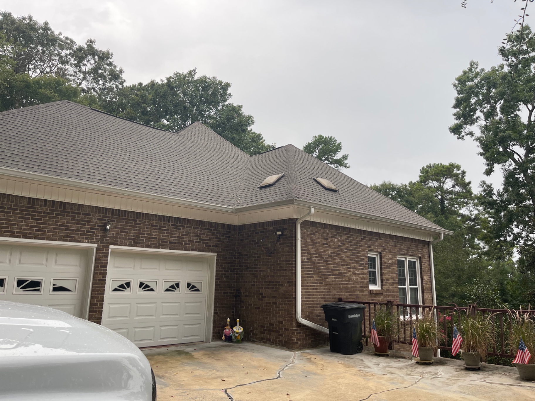 Driveway view of a large brick home with a multi-gable architectural shingle roof and skylights