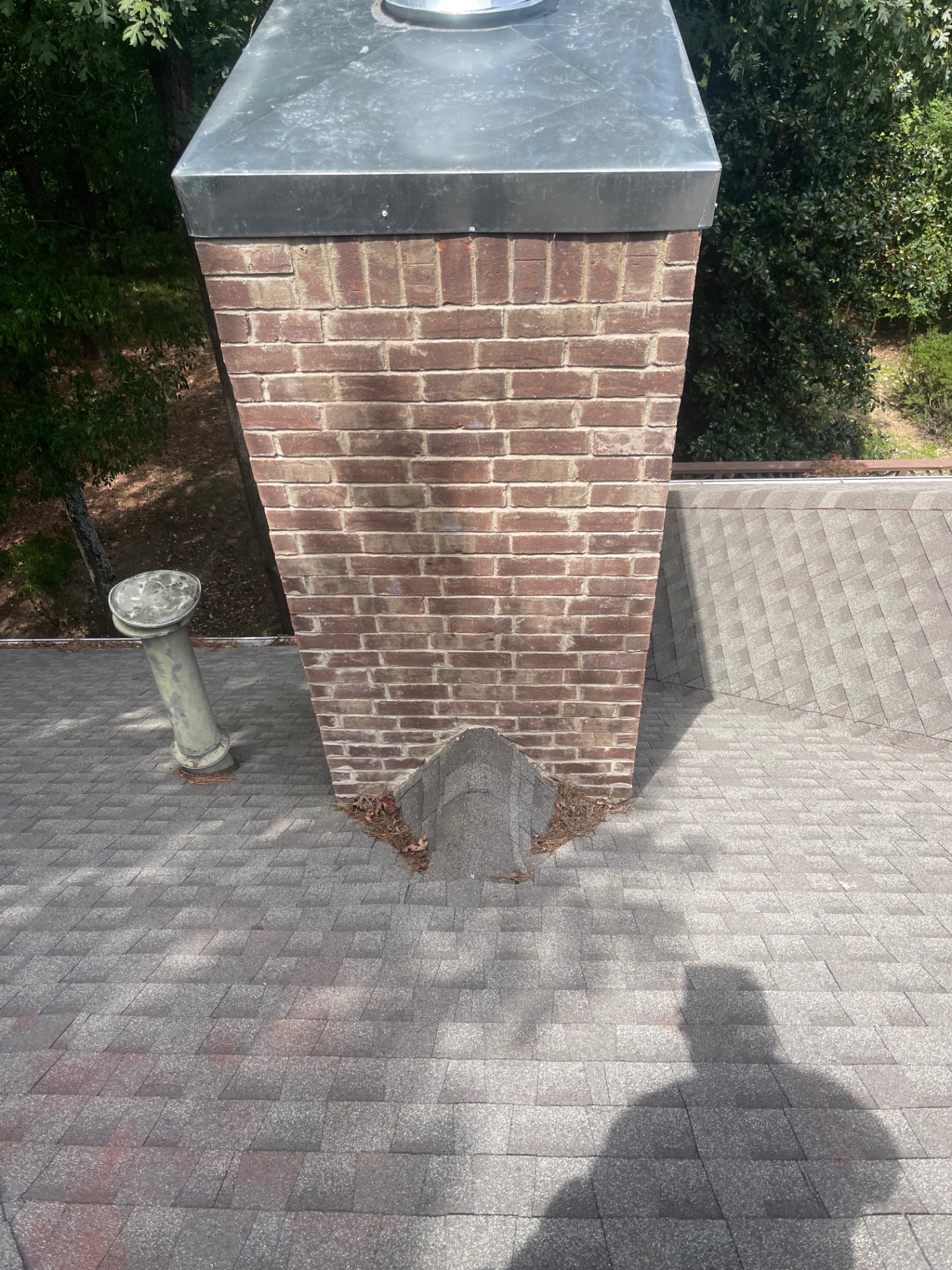 Close-up view of a brick chimney with newly installed metal cap on a shingle roof