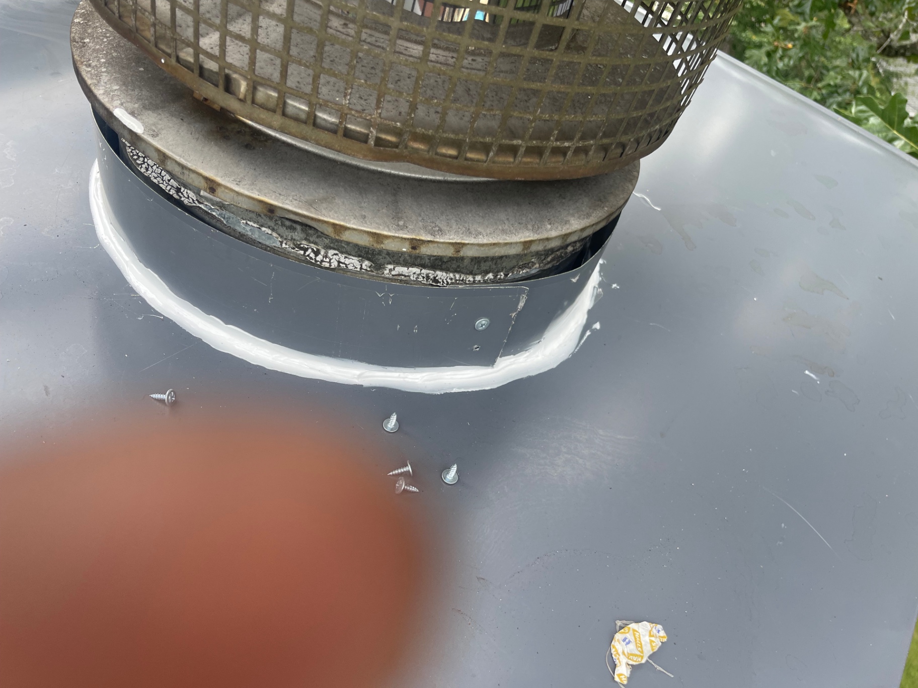 Detail of a freshly sealed chimney cap base on a new metal crown